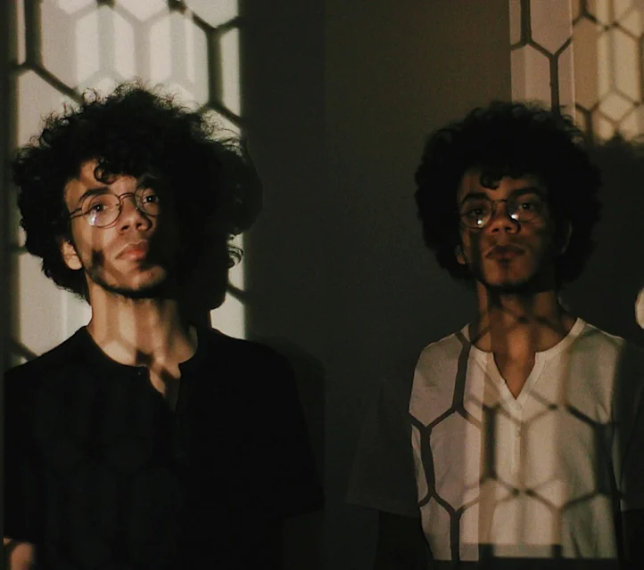 Identical twins side-by-side, one well illuminated, one in shadow.