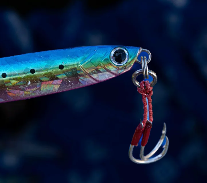 An iridescent fishing lure with hooks dangling from it.