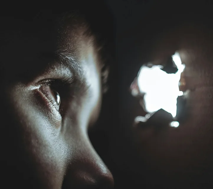 A person peering through a small hole.