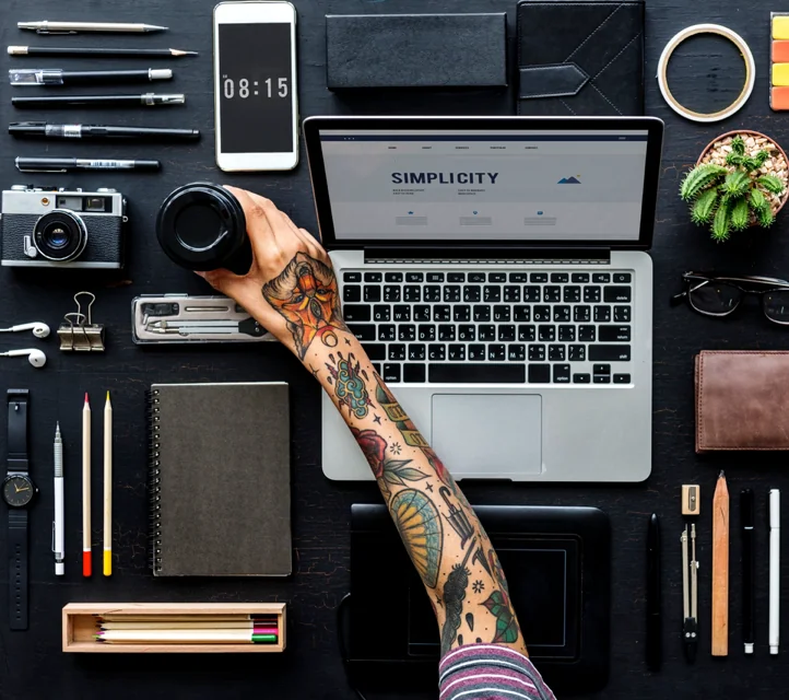 An arm reaching across a digital workstation with items arrayed in too-perfect order.