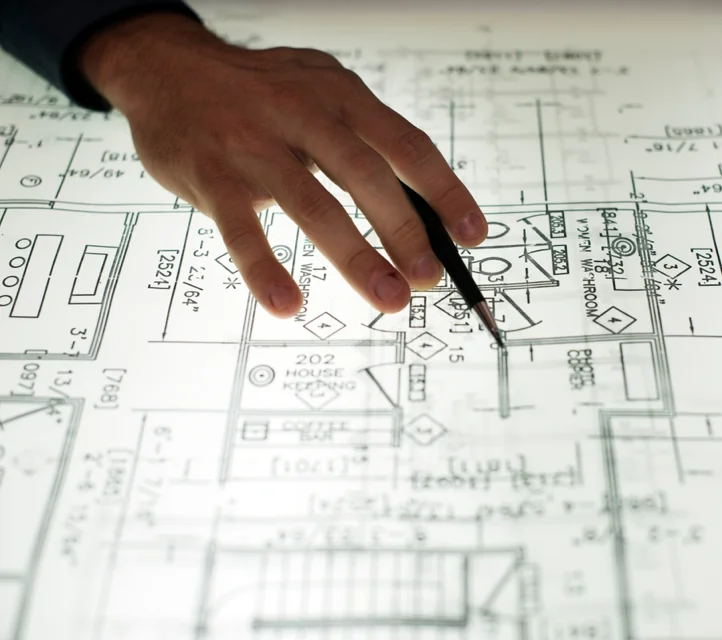 A hand with a pen going over a floorplan.