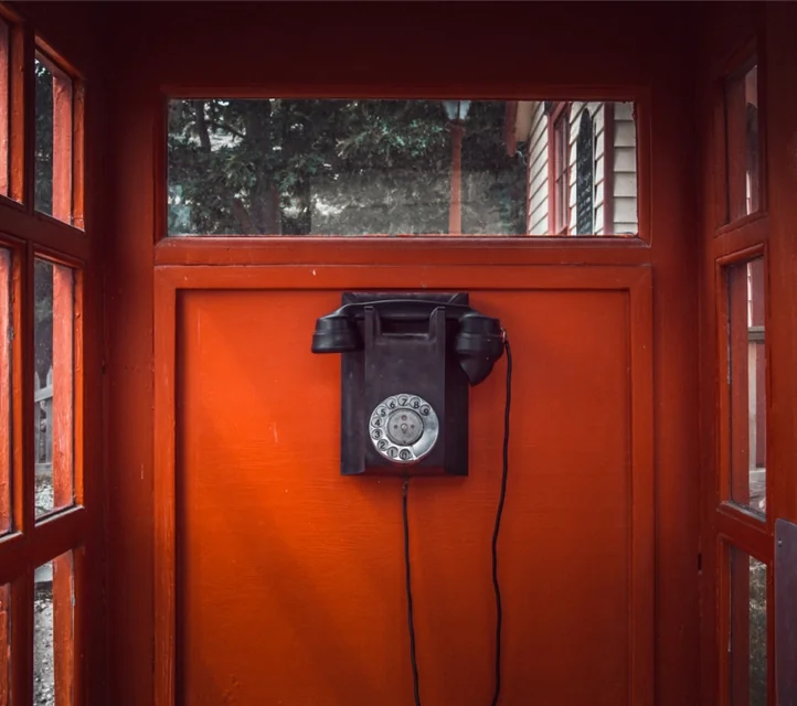 An antique telephone in a booth.