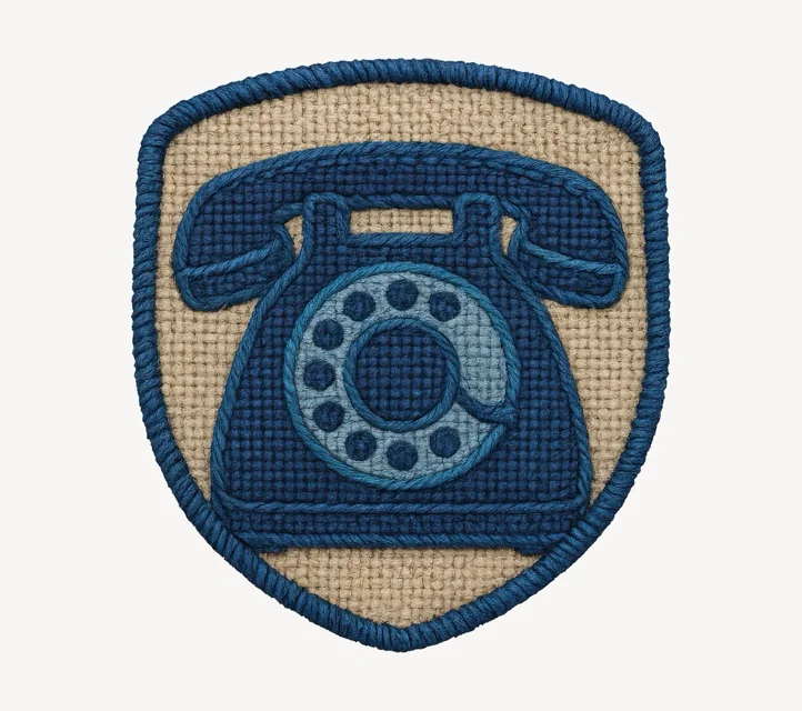 A cross-stitched shield with a telephone as its insignia.